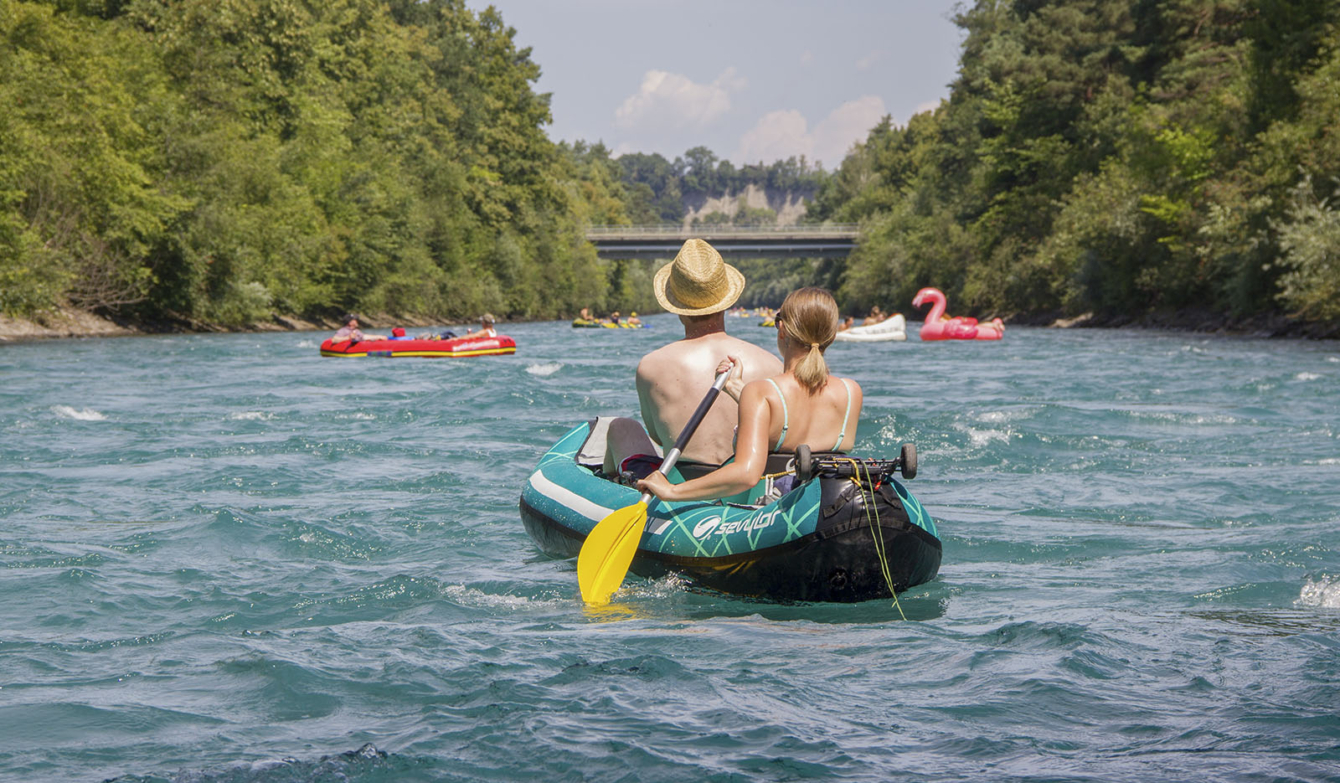 Foto: Schlauchboot-Kanu und gelber Paddel auf der Aare mit einem jungen Paar.